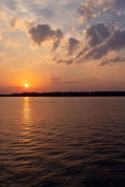 Doğanın güzelliğini ve o anın huzurunu gözler önüne seren, nehrin üzerinde çarpıcı bir günbatımı manzarası.