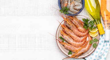 Beyaz ve gül şarabı eşliğinde karides, langoustine ve alabalık bifteği gibi taze deniz ürünlerinin üst görüntüsü. Kopyalama alanı olan düz