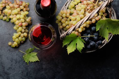 Şarap bardakları, şişeler ve üzümler sepette. Kopyalama alanı olan düz