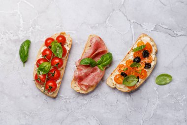 Lezzetli bir bruschetta seti sulu domates, peynir ve lezzetli prosciutto ile süslenmiş. Düz yatıyordu