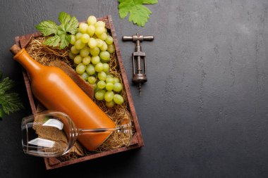 Kırsal ahşap bir kutuda sunulan kırmızı şarap şişesi ve taze üzüm. Kopyalama alanı olan düz