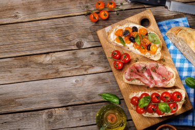 Bahçe masasında sulu domatesler, peynir ve baharatlı jambonla süslenmiş nefis bir sandviç seti. Kopyalama alanı olan düz