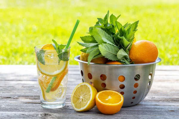 屋外のガーデンテーブルで提供される自家製レモネードをリフレッシュします 新鮮な柑橘類と庭のミントと冷たい夏の飲み物 — ストック写真