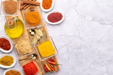 Various dried spices in small bowls on stone table with copy space. Flat lay