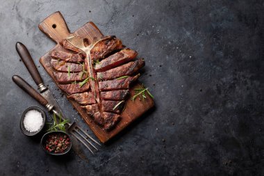 Izgara biftekli biftek. Bitki ve baharatla dilimlenmiş T-bone. Üst görünüm düzlüğü kopyalama alanı ile yatıyordu