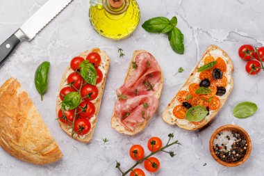 Lezzetli bir bruschetta seti sulu domates, peynir ve lezzetli prosciutto ile süslenmiş. Düz yatıyordu