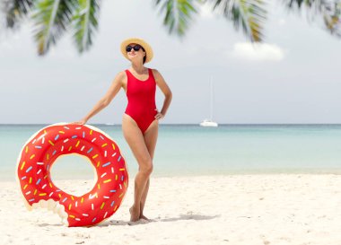 Beautiful young woman with inflatable donut ring relaxing on sea beach. Summer vacation. With copy space