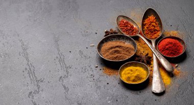 Various spices in bowls and spoons on stone table. With copy space for your menu or recipe
