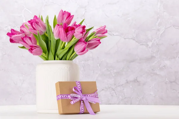 新鮮なピンクのチューリップの花花束とギフトボックス コピースペースのある白い木製のテーブルで — ストック写真