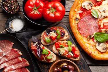 İtalyan mutfağı. Pepperoni pizza, zeytin ve antipasto tostları. Tahta masanın üzerinde yatıyordu.