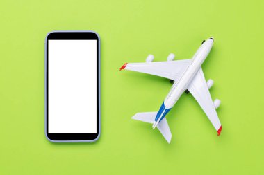 Seyahat ve online rezervasyon konsepti. Akıllı telefon ve uçak oyuncağı kopyalama alanı olan yeşil masada.
