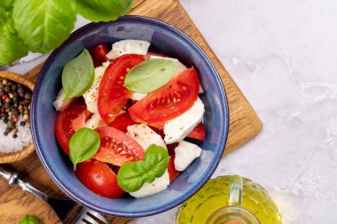 Olgun domatesli Caprese salatası, mozzarella peyniri ve bahçe fesleğeni. Düz yatıyordu