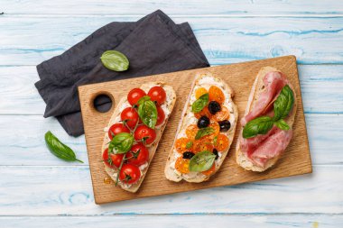 Lezzetli bir bruschetta seti sulu domates, peynir ve lezzetli prosciutto ile süslenmiş. Düz yatıyordu