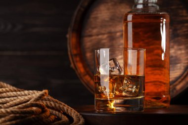 Bardak ve şişe konyak, viski ya da altın rom. Kopya alanı olan eski ahşap fıçının önünde.