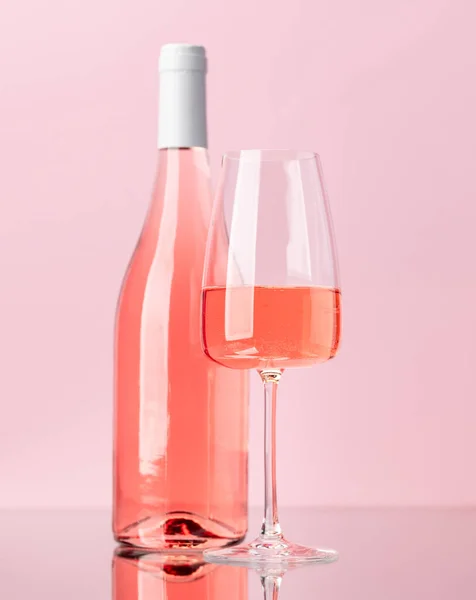 Rose wine bottle and wine glass over rose background
