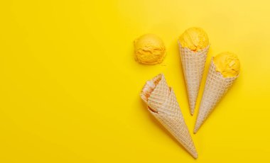 Lezzetli waffle külahlarında limonlu dondurma, her tat için bir ikram. Fotokopi alanı olan sarı arkaplan üzerinde düz uzanır