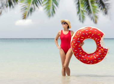 Beautiful young woman with inflatable donut ring relaxing on sea beach. Summer vacation. With copy space