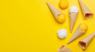 Lezzetli waffle külahlarında çeşitli dondurma aromaları, her tat tomurcuğu için bir ikram. Fotokopi alanı olan sarı arkaplan üzerinde düz uzanır