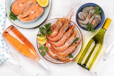 Beyaz ve gül şarabı eşliğinde karides, langoustines ve alabalık bifteği gibi taze deniz ürünlerinin üst görüntüsü