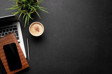 Laptop bilgisayarı, kahve ve malzemelerle dolu ofis masası. Kopyalama alanı olan üst görünüm. Düz yatıyordu