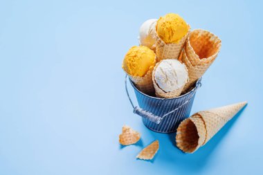 Lezzetli waffle külahlarında limonlu dondurma, her tat için bir ikram. Kopyalama alanı olan mavi arkaplan