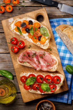 Bahçe masasında sulu domatesler, peynir ve baharatlı jambonla süslenmiş nefis bir sandviç seti. Düz yatıyordu