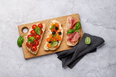 Lezzetli bir bruschetta seti sulu domates, peynir ve lezzetli prosciutto ile süslenmiş. Düz yatıyordu