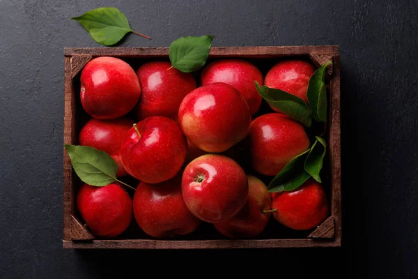 Wooden box with fresh red apples on stone table. Flat lay
