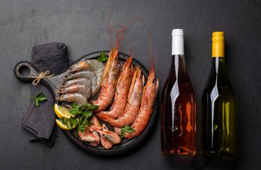 Beyaz ve gül şarabı eşliğinde karides, langoustine ve alabalık bifteği gibi taze deniz ürünlerinin üst görüntüsü. Düz yatıyordu