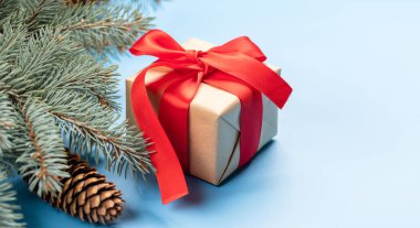 Noel ağacı dalı ve hediye kutusu mavi arkaplanda ve tebrik mesajları için yer var