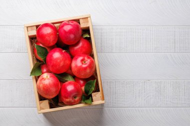 Tahta masada taze kırmızı elmalar olan tahta kutu. Kopyalama alanı olan düz