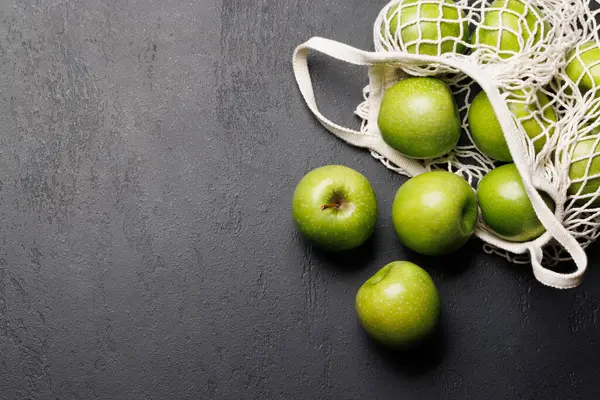 有新鲜绿色苹果的网袋放在石桌上 有复制空间 — 图库照片