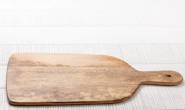 Wooden cutting board on white kitchen table. With copy space