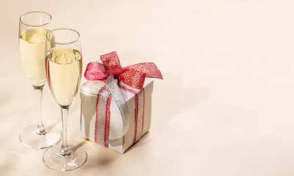Two champagne glasses and gift box. Christmas greeting card template with copy space