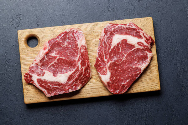 Raw ribeye steaks with savory spices. Flat lay