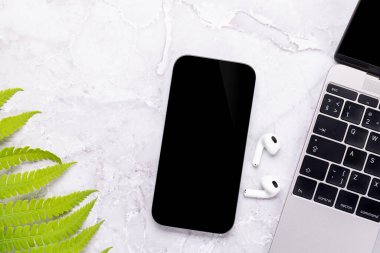 Yeşil doğa yapraklarıyla çevrili bir masada boş ekranı olan akıllı telefon, mükemmel tasarım modeli.