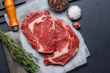 Raw ribeye steaks with savory spices. Flat lay clipart