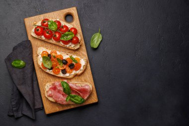 Lezzetli bir bruschetta seti sulu domates, peynir ve lezzetli prosciutto ile süslenmiş. Kopyalama alanı olan düz