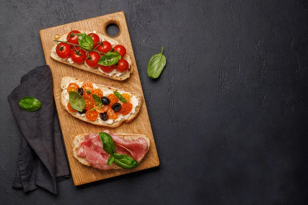Lezzetli bir bruschetta seti sulu domates, peynir ve lezzetli prosciutto ile süslenmiş. Kopyalama alanı olan düz