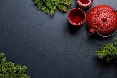 Çaydanlık, kupa ve köknar ağacı dalları samimi bir sahne oluşturuyor. Fotokopi alanı olan düz bir yer. Noel kartı şablonu
