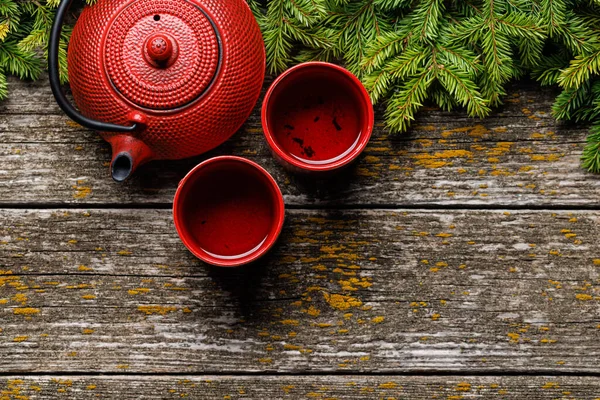 Çaydanlık, kupa ve köknar ağacı dalları samimi bir sahne oluşturuyor. Fotokopi alanı olan düz bir yer. Noel kartı şablonu