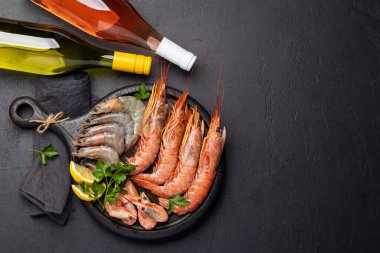 Beyaz ve gül şarabı eşliğinde karides, langoustine ve alabalık bifteği gibi taze deniz ürünlerinin üst görüntüsü. Kopyalama alanı olan düz