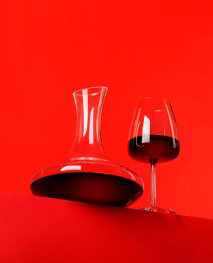 Kırmızı şarap zarafeti: canlı kırmızı arka plana karşı dekan ve şarap kadehi. Kopyalama alanı ile