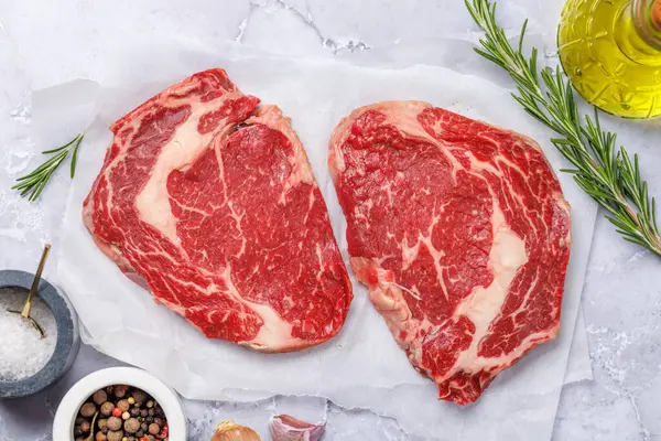 Stock image Raw ribeye steaks with savory spices. Flat lay