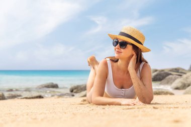 Woman lying on the sea beach enjoying and relaxing in summer
