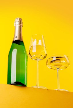 Şampanya zarafeti, cam ve şişe, parlak sarı bir arka plana karşı. Kopyalama alanı ile