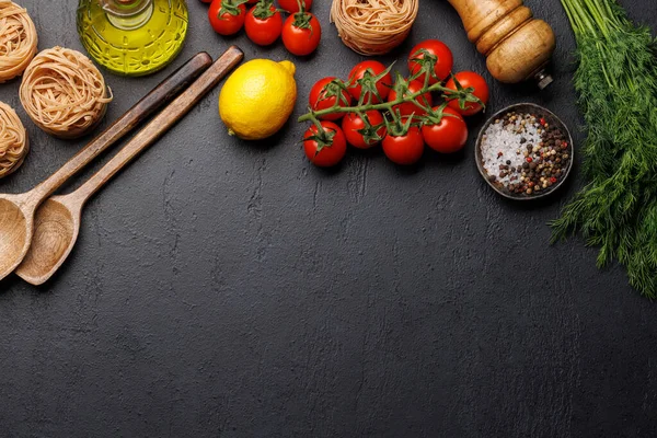 Cooking scene: Cherry tomatoes, pasta, spices on table. Flat lay with copy space
