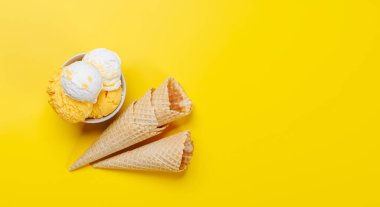 Çeşitli dondurma tatları ve nefis waffle külahları. Her tat için bir ikram. Fotokopi alanı olan sarı arkaplan üzerinde düz uzanır