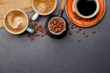Kavrulmuş kahve çekirdekleri ve çeşitli espresso fincanları. Kopyalama alanı olan düz