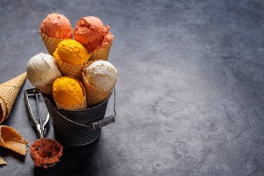 Lezzetli waffle külahlarında çeşitli dondurma aromaları, her tat tomurcuğu için bir ikram. Kopyalama alanı olan taş arkaplan